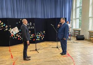 Nauczyciele i uczniowie w czasie uroczystości na sali gimnastycznej