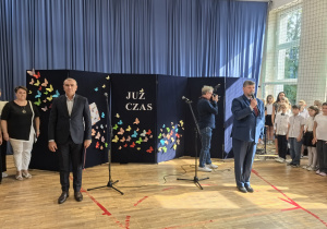 Nauczyciele i uczniowie w czasie uroczystości na sali gimnastycznej