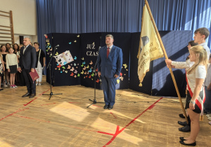 Nauczyciele i uczniowie w czasie uroczystości na sali gimnastycznej