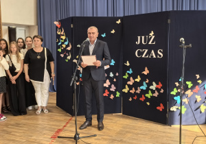Nauczyciele i uczniowie w czasie uroczystości na sali gimnastycznej