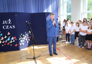 Nauczyciele i uczniowie w czasie uroczystości na sali gimnastycznej