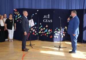 Nauczyciele i uczniowie w czasie uroczystości na sali gimnastycznej