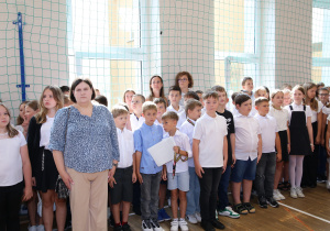 Nauczyciele i uczniowie w czasie uroczystości na sali gimnastycznej