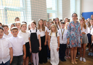 Nauczyciele i uczniowie w czasie uroczystości na sali gimnastycznej