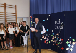 Nauczyciele i uczniowie w czasie uroczystości na sali gimnastycznej