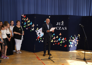 Nauczyciele i uczniowie w czasie uroczystości na sali gimnastycznej