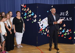 Nauczyciele i uczniowie w czasie uroczystości na sali gimnastycznej