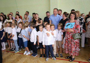 Nauczyciele i uczniowie w czasie uroczystości na sali gimnastycznej