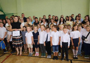 Nauczyciele i uczniowie w czasie uroczystości na sali gimnastycznej