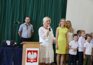 Nauczyciele i uczniowie w czasie uroczystości na sali gimnastycznej