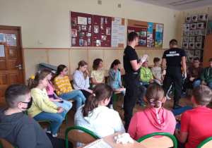 Uczniowie klasy IV a siedzą na krzesłach słuchają informacji przekazywanych przez Szymona i Borysa.