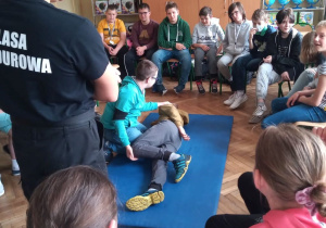 Uczeń klasy 6a - Oliwier, uczy się położyć poszkodowanego w pozycji bezpiecznej.