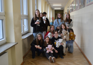 Uczniowie z pluszowymi maskotkami.