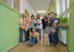 Uczniowie z pluszowymi maskotkami.