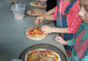 Dzieci przygotowujące pizze.