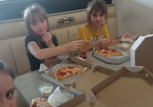 Dzieci jedzące pizze.