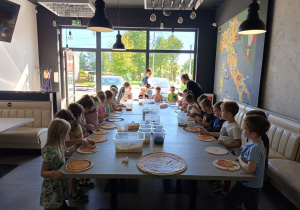Dzieci wykonujące w pizzeri w własnoręcznie pizzę