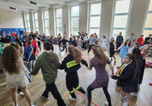 Uczniowie w przebraniach karnawałowych bawiący się na sali gimnastycznej