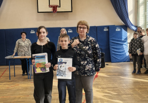 Grupa nauczycieli i uczniów z dyplomami na sali gimnastycznej
