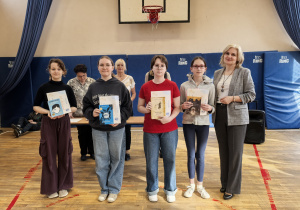 Grupa nauczycieli i uczniów z dyplomami na sali gimnastycznej