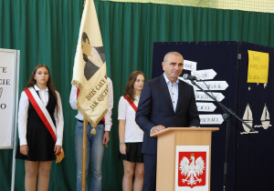 Uczniowie i nauczyciele w czasie uroczystości na sali gimnastycznej