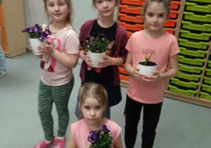 Uczniowie pozujący z kwiatkami w doniczkach.