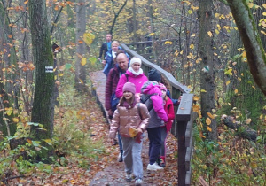 Uczniowie i opiekunowie idący ścieżka w lesie
