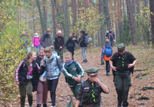 Uczniowie i opiekunowie idący ścieżka w lesie